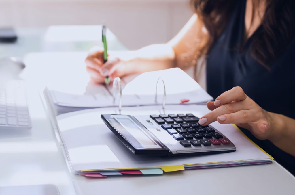 Businesswoman calculating taxes and writing financial notes on a desk.