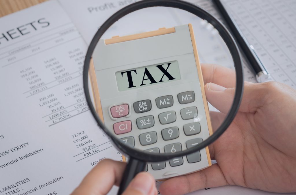Ręka trzymająca kalkulator z napisem TAX, symbolizujący płatność Corporation Tax